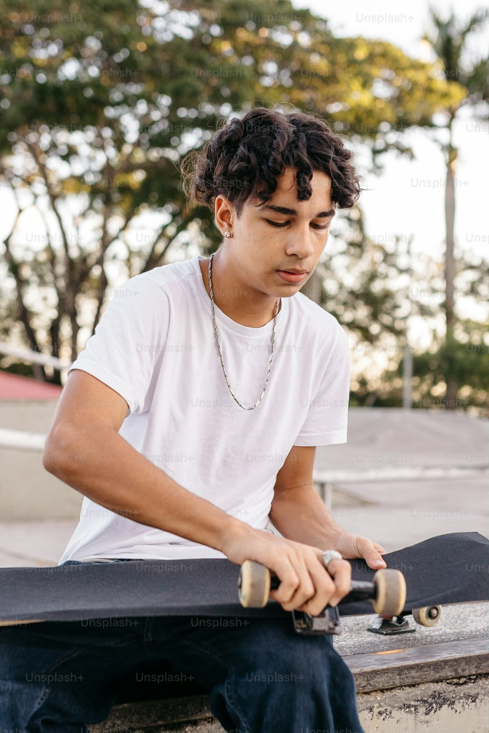 Un giovane seduto su una sporgenza che tiene uno skateboard