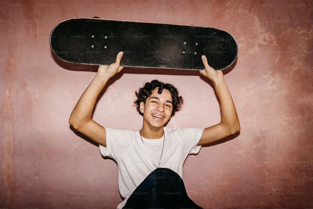 a young man holding a skateboard above his head