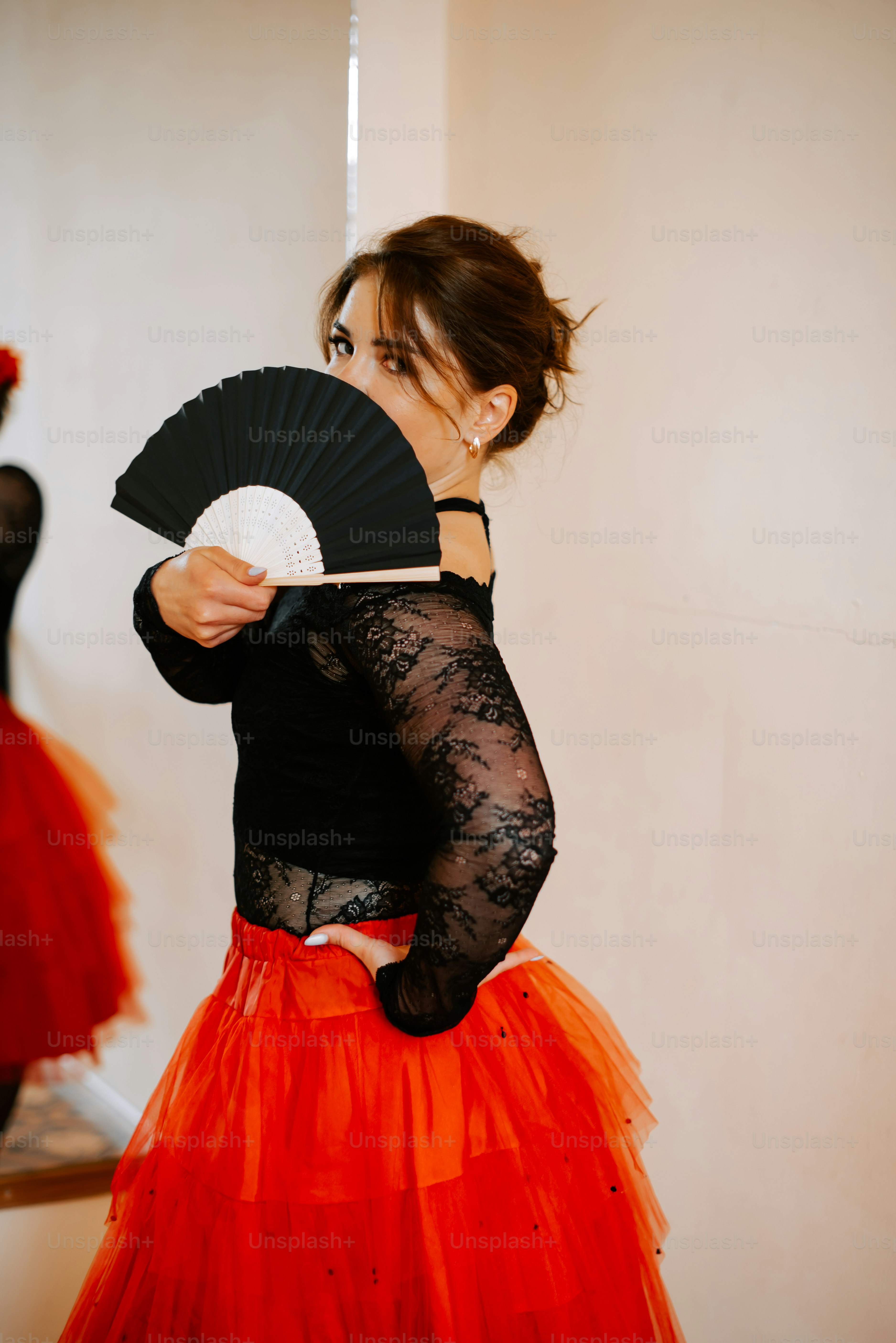 Une femme en tutu rouge tenant un éventail noir