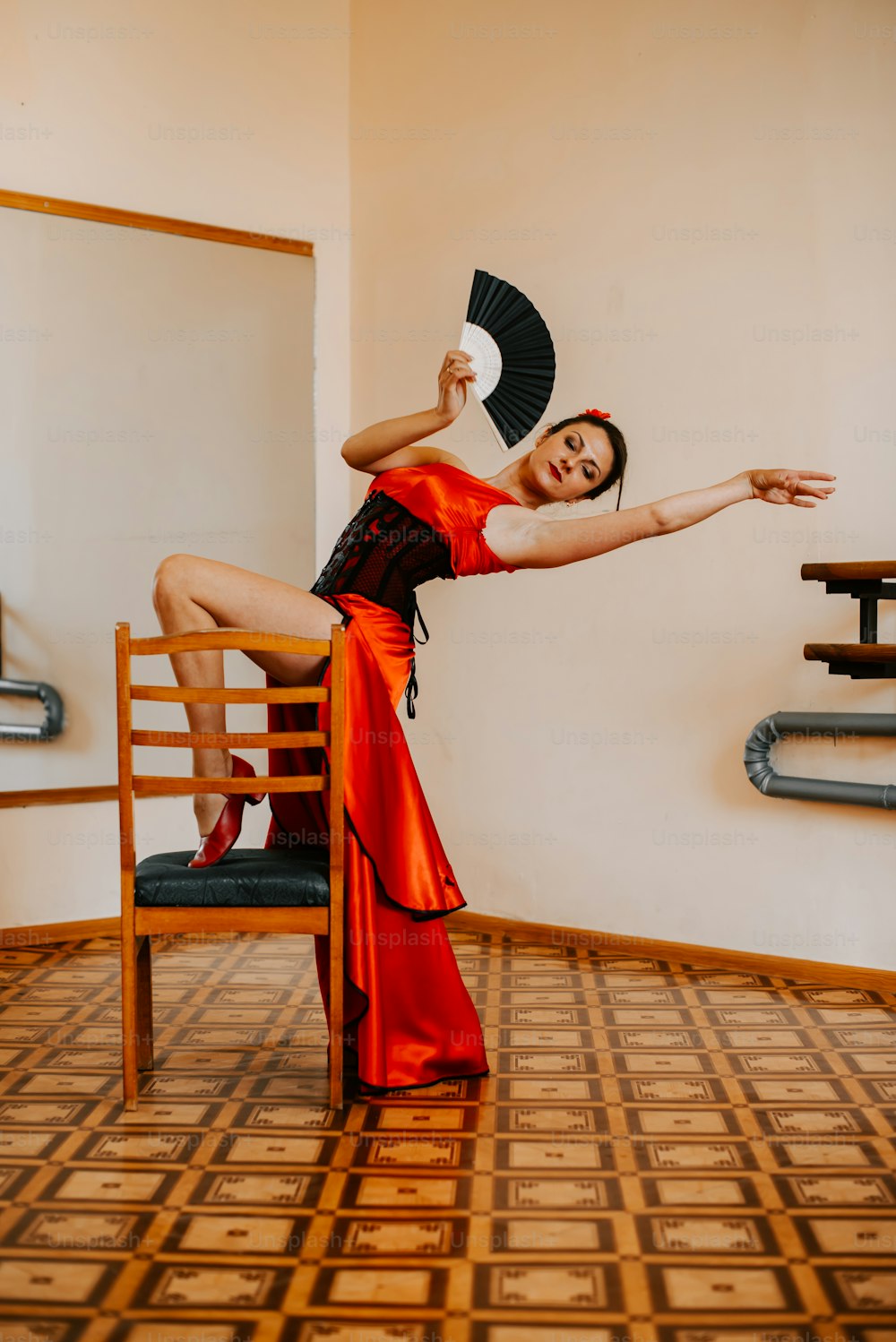 a woman in a red dress is dancing on a chair