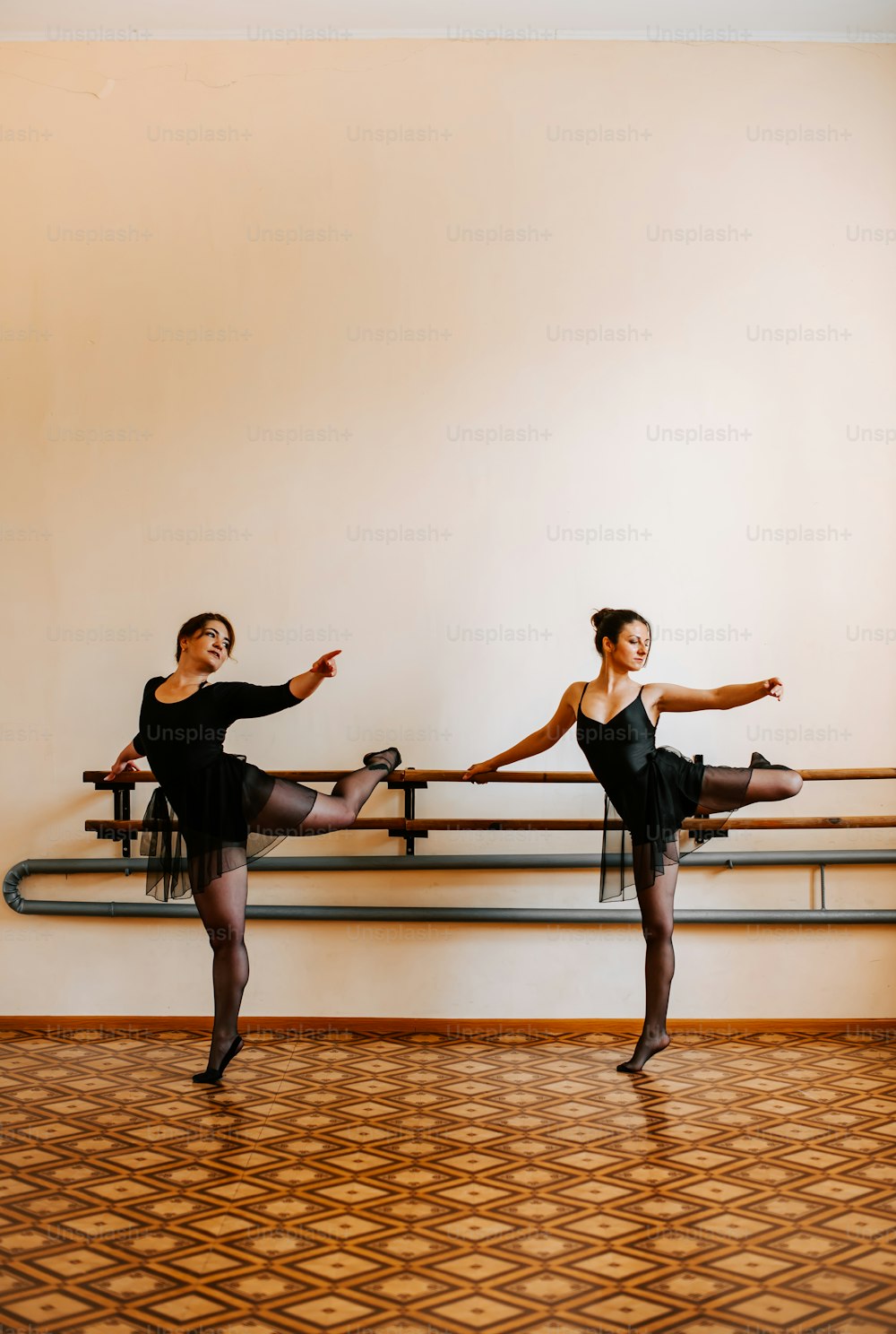 two ballerinas in black leotards in a dance studio