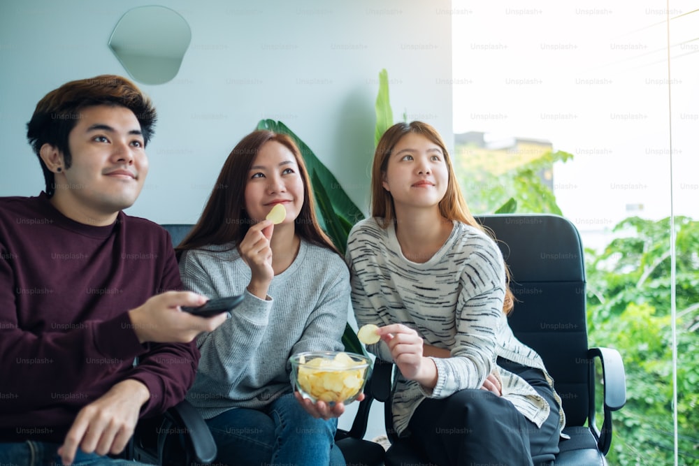 Amigos comiendo papas fritas mientras ven la televisión juntos