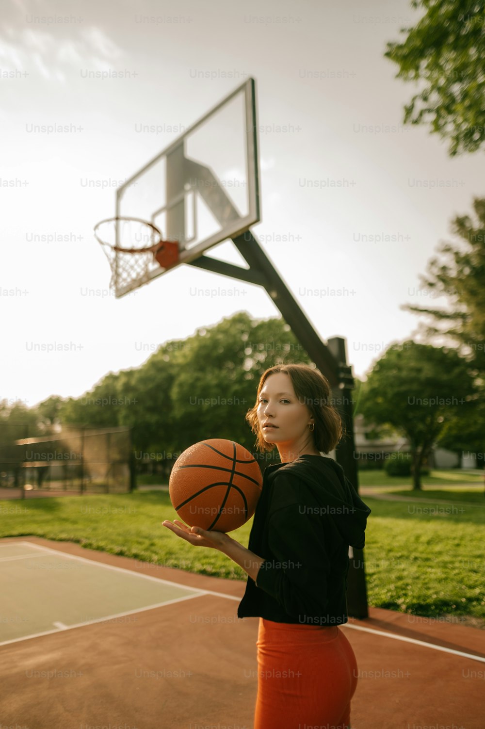 Une femme tenant un ballon de basket sur un terrain de basketball