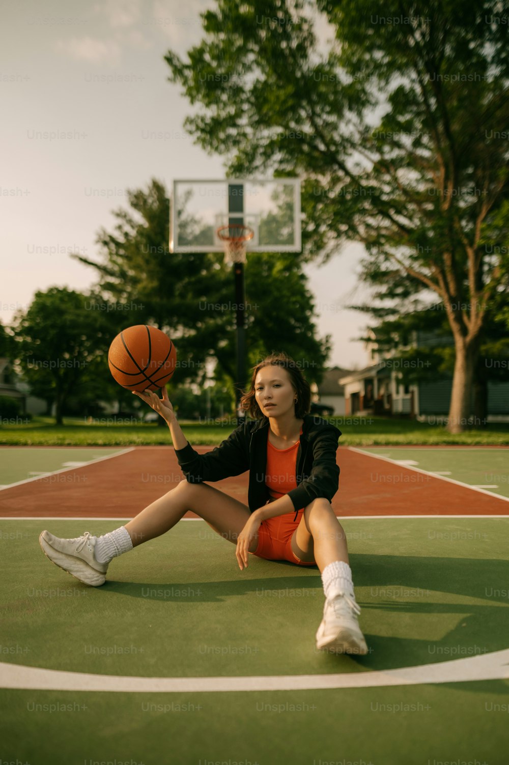 a woman sitting on a basketball court holding a basketball