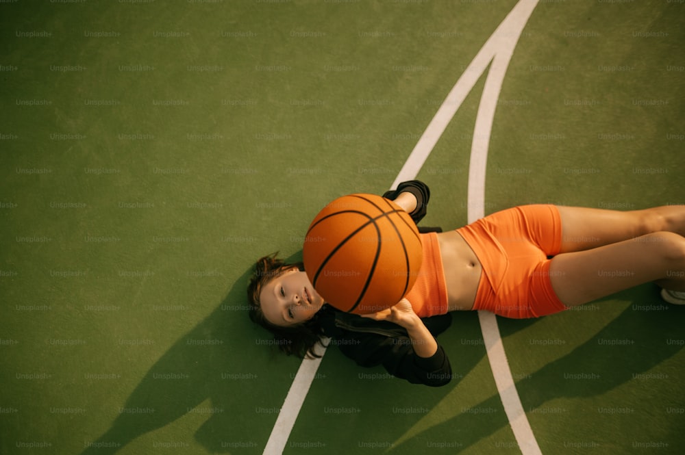 a woman laying on a court with a basketball on her head