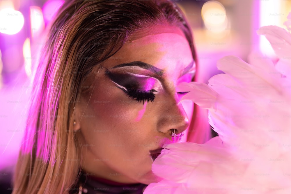 a woman with pink makeup and feathers on her face