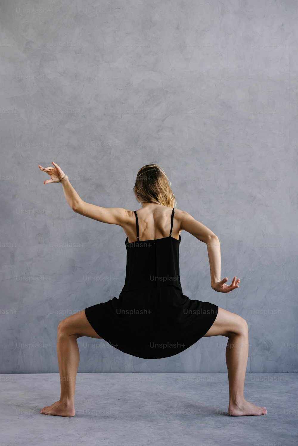 Una mujer con un vestido negro está haciendo una pose de yoga