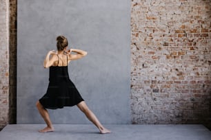 a woman in a black dress is doing a yoga pose