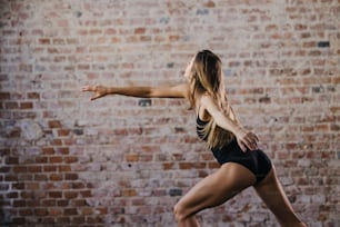 a woman in a black top is doing a yoga pose