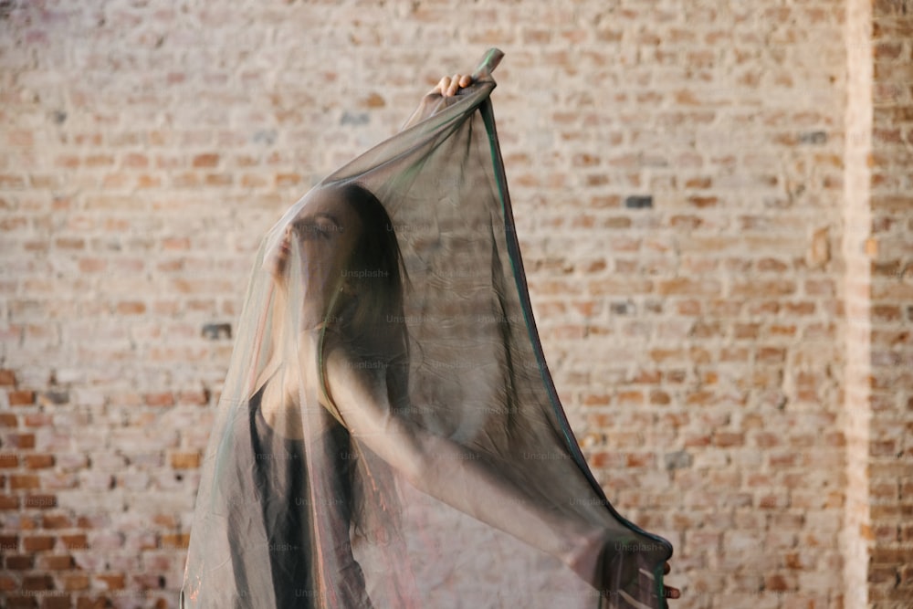 a woman in a veil is standing in front of a brick wall