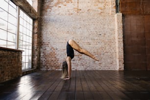 a woman doing a handstand on a wooden floor