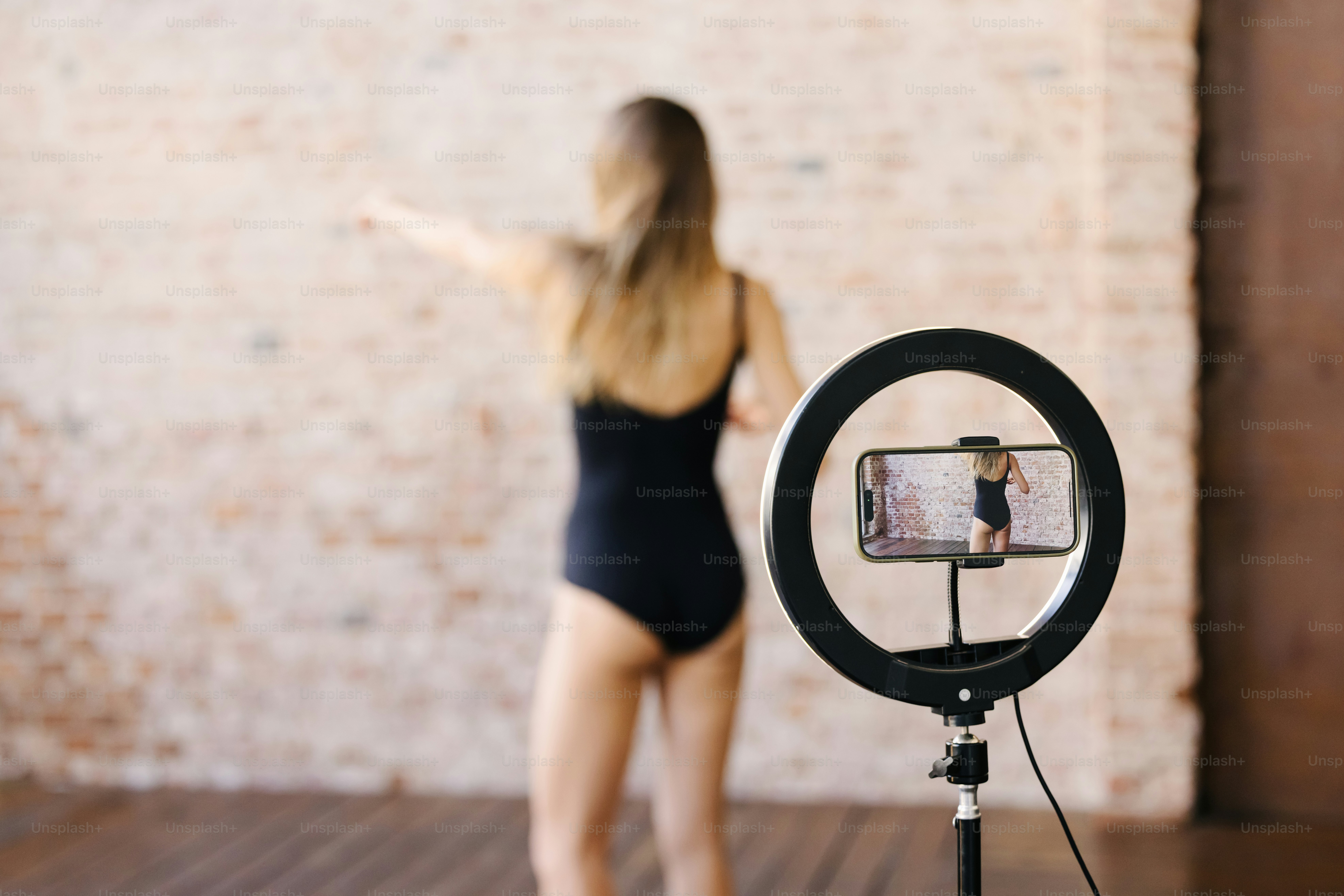 a woman in a black bodysuit standing next to a camera