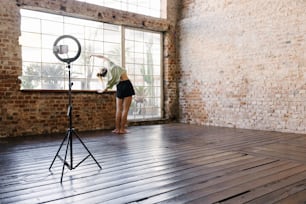 Une femme debout devant une caméra sur un plancher en bois