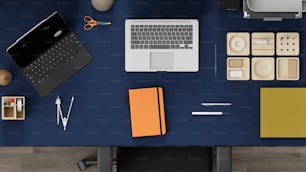 a desk with a laptop, notebook and other office supplies