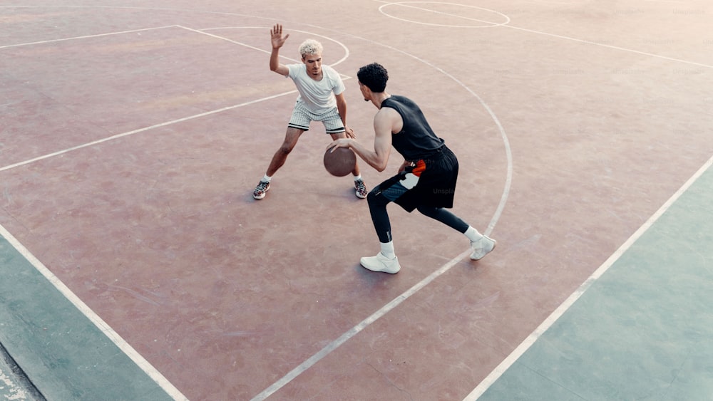 Due uomini che giocano a basket su un campo da basket