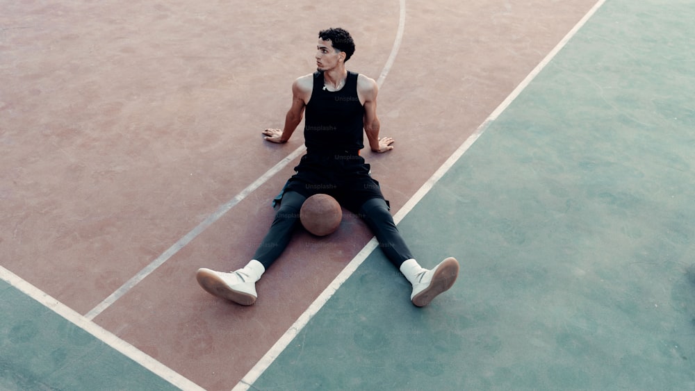 a man sitting on top of a basketball court