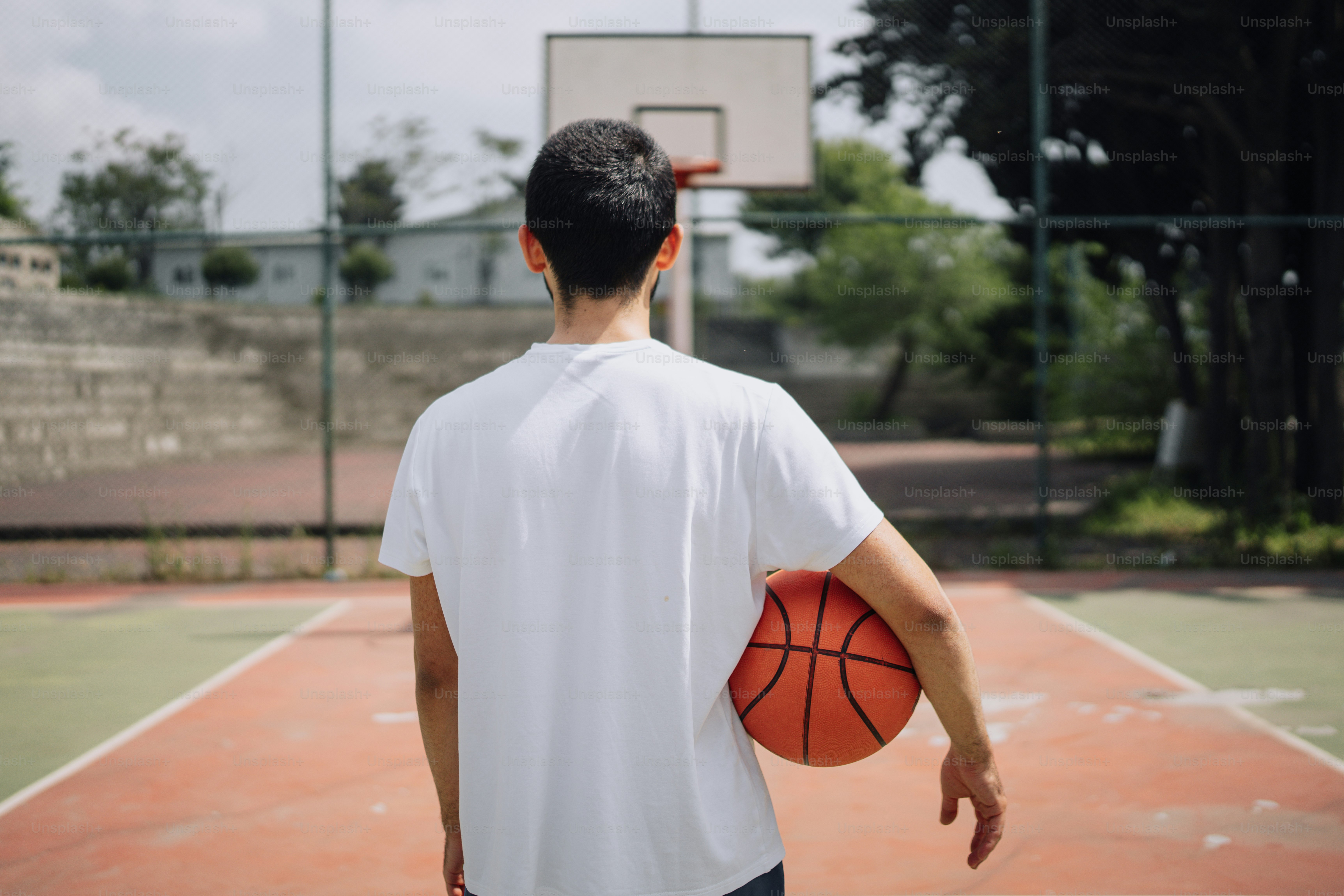 Un homme tenant un ballon de basket sur un terrain de basket-ball