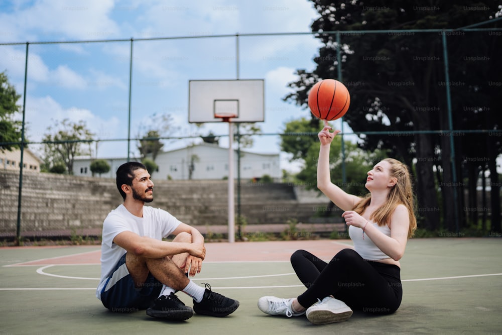 a man and a woman sitting on a basketball court