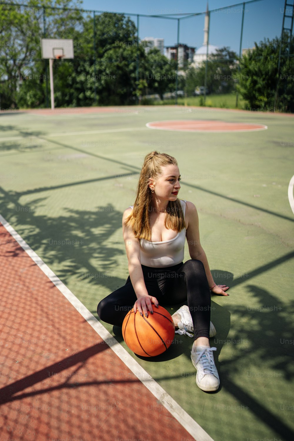 a woman sitting on the ground with a basketball