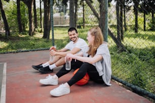 Un hombre y una mujer sentados en una cancha de baloncesto