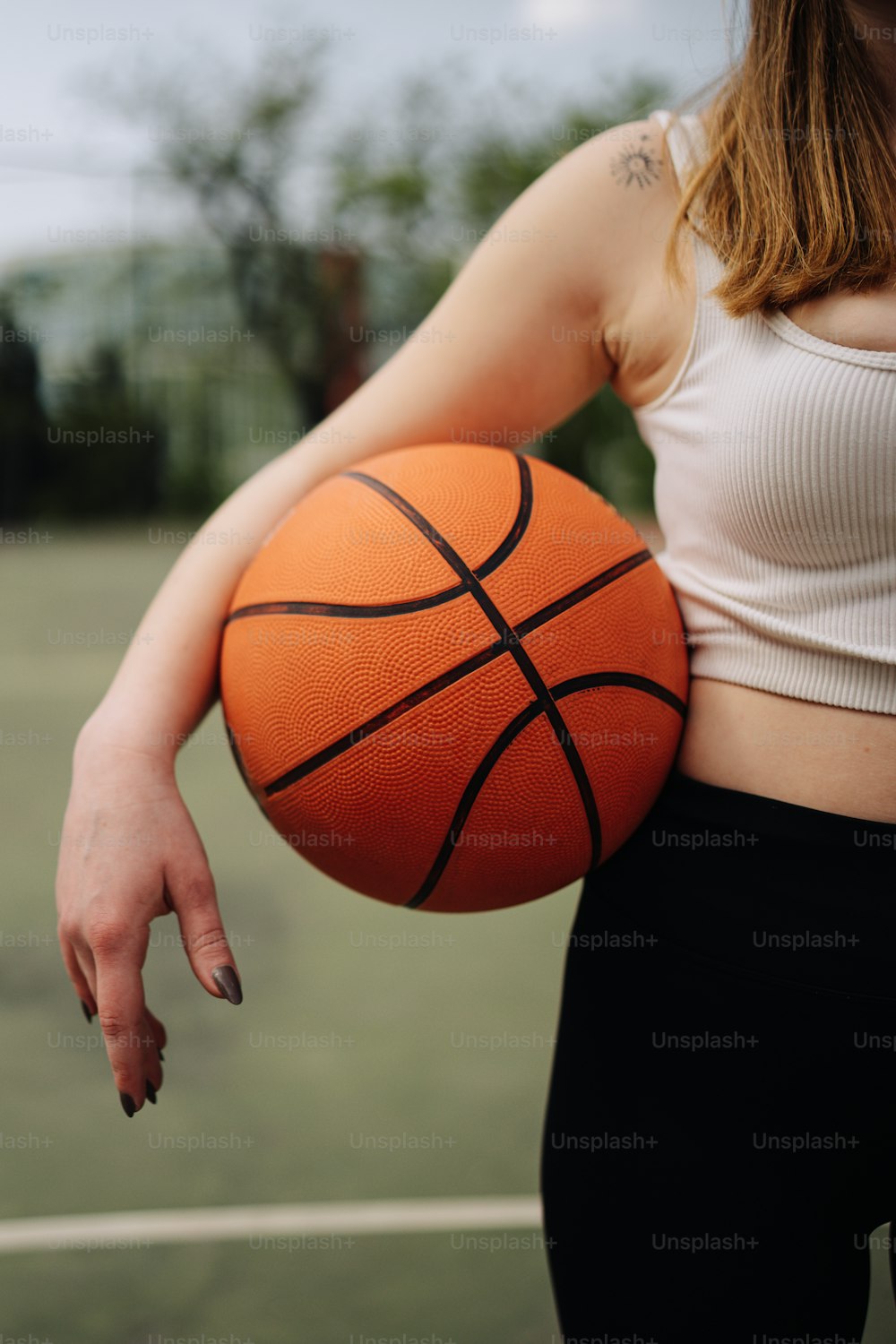 a woman holding a basketball on a tennis court