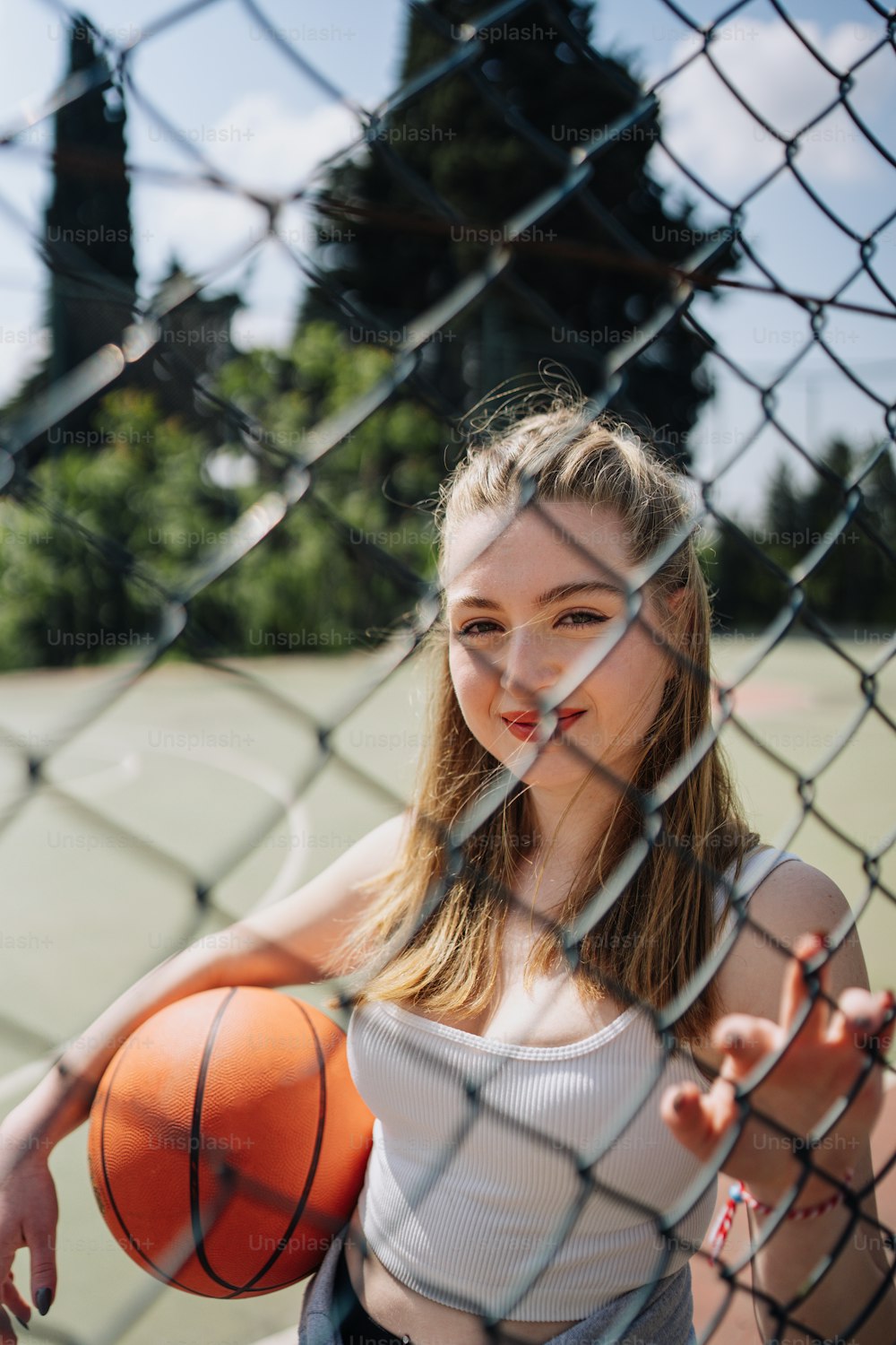a woman holding a basketball behind a fence