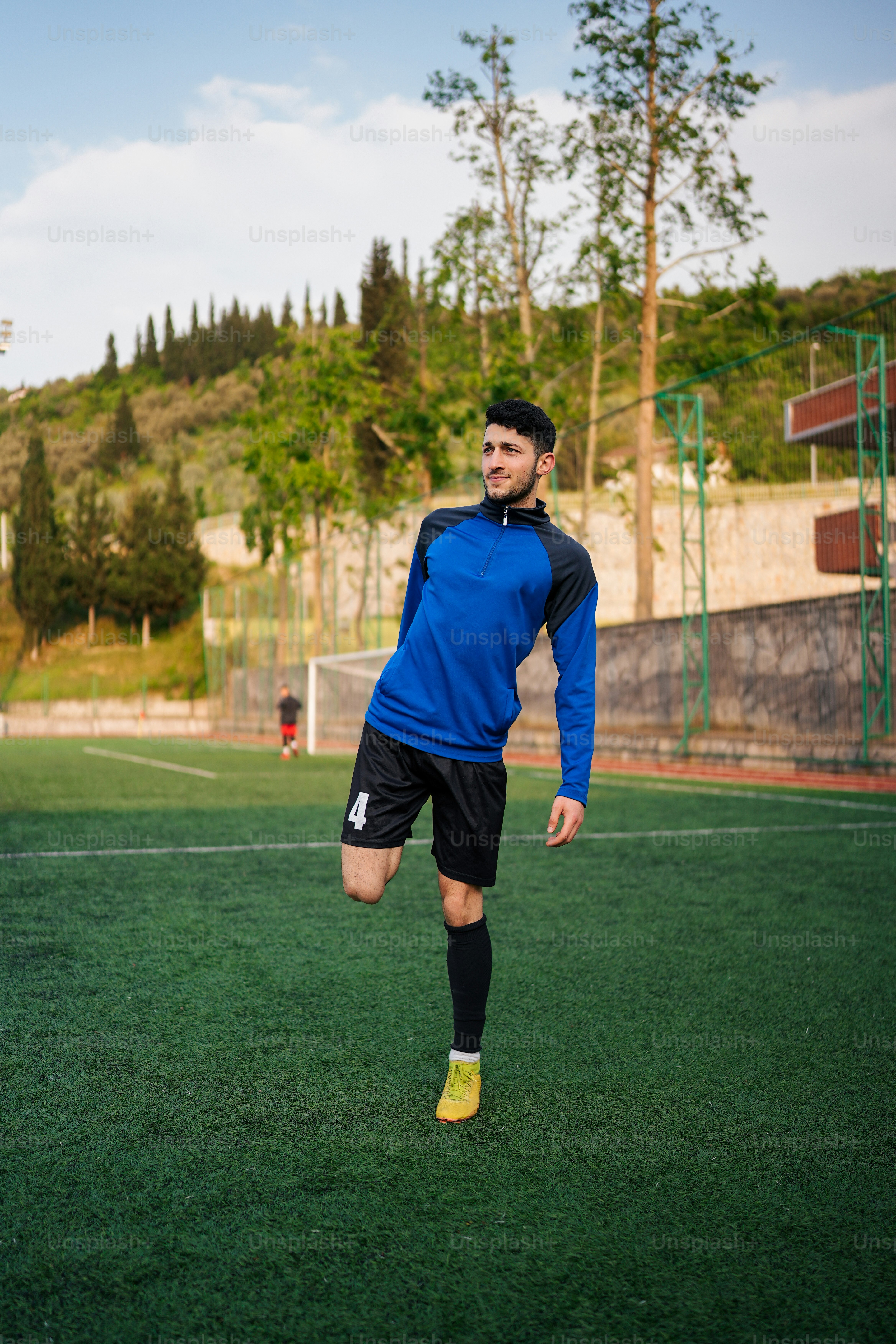 a man in a blue shirt and black shorts kicking a soccer ball