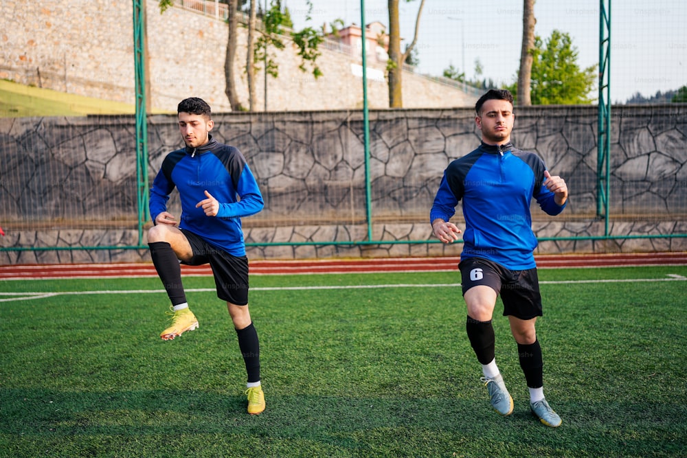 a couple of men kicking a soccer ball around a field