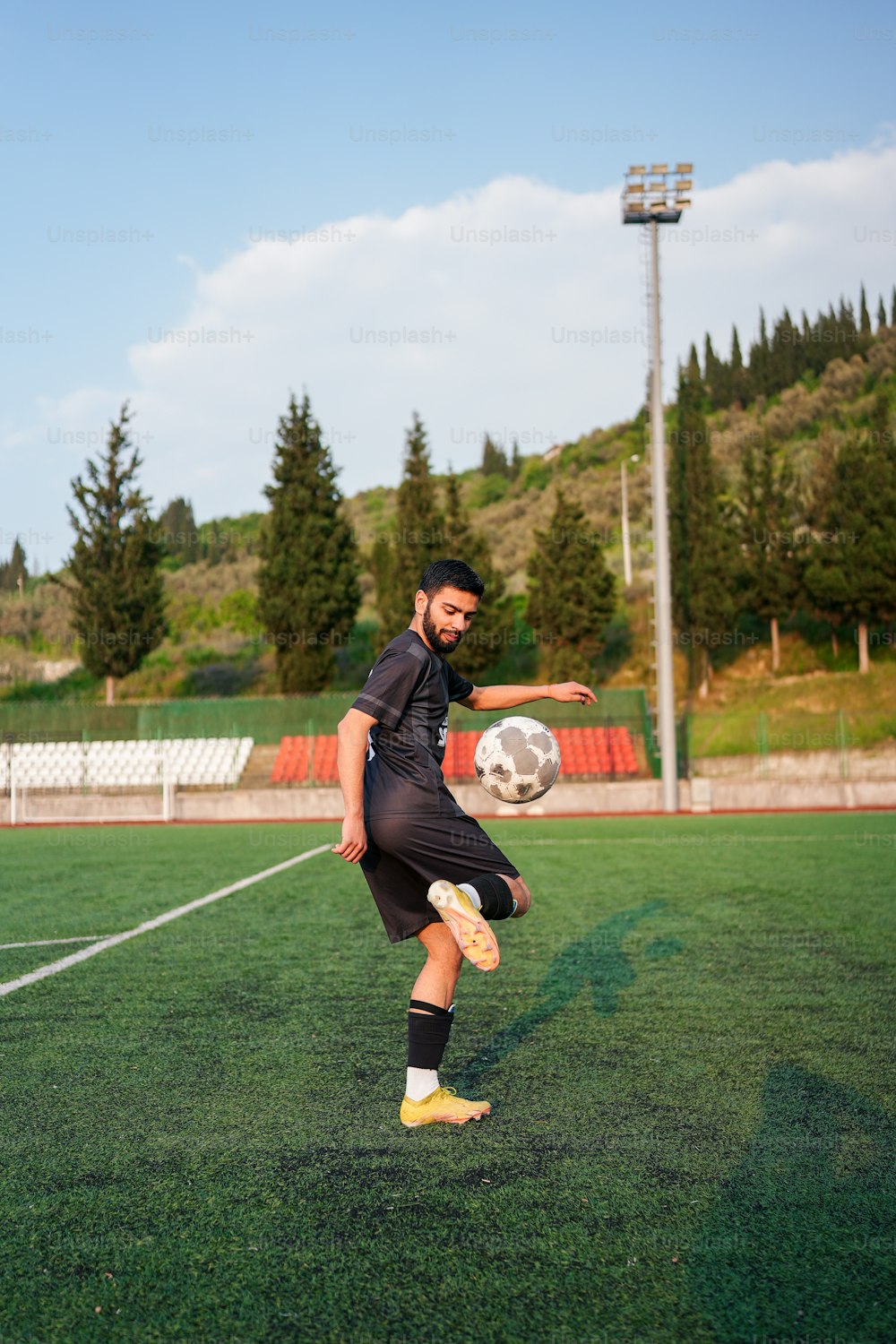 um homem chutando uma bola de futebol em um campo