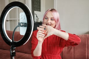 a woman with pink hair is holding a camera