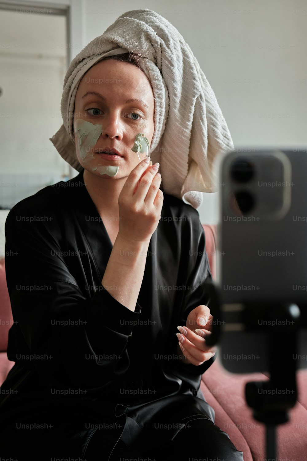 a woman with a towel on her head is shaving her face