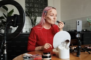 Una mujer sentada en una mesa con pinceles de maquillaje frente a ella