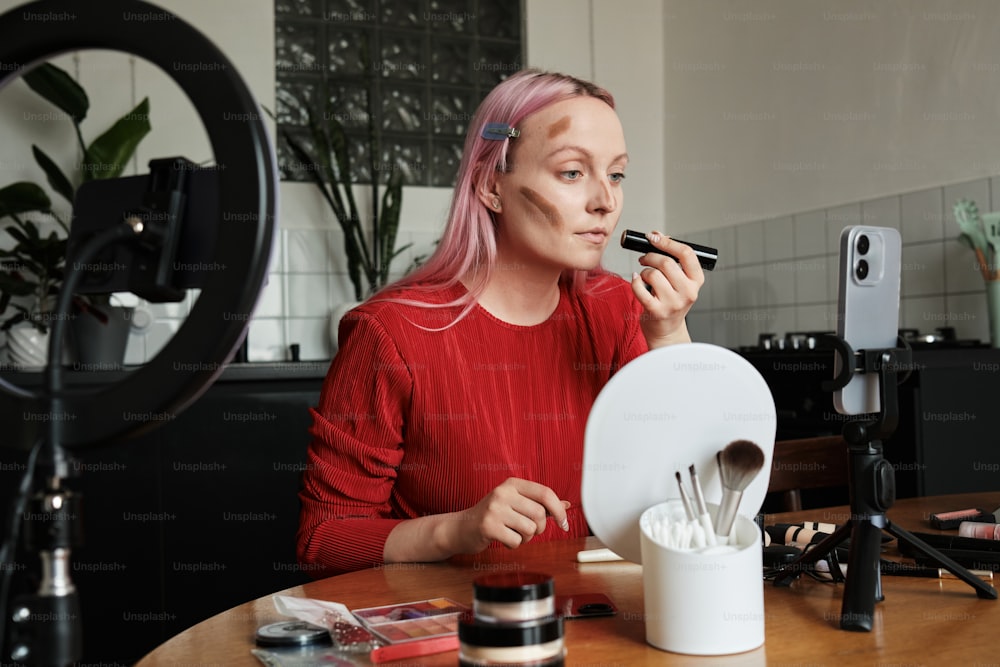a woman sitting at a table with makeup brushes in front of her