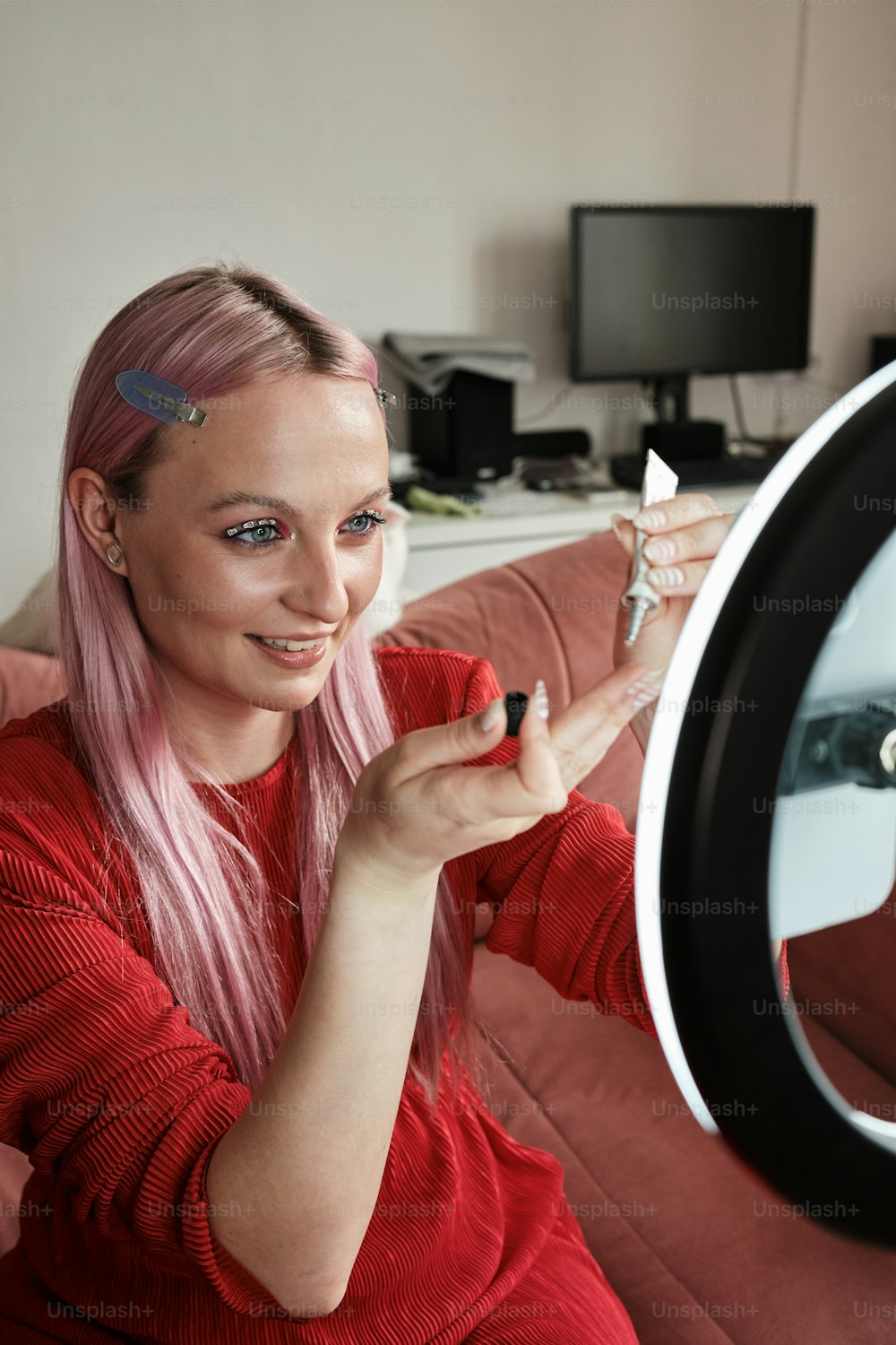 a woman with pink hair is holding a mirror