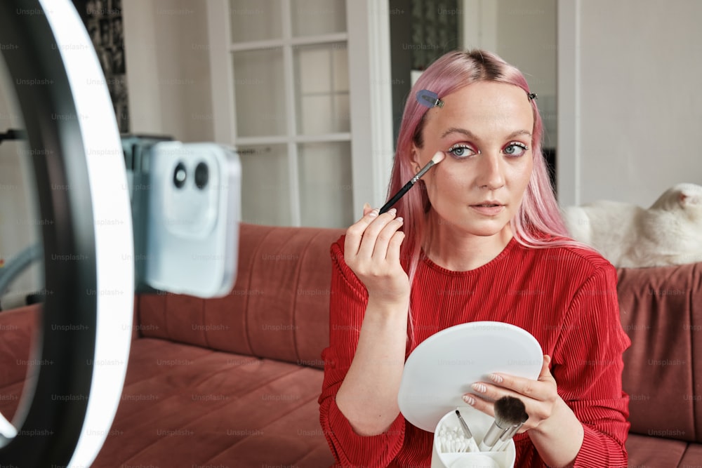 a woman with pink hair is holding a plate and brush