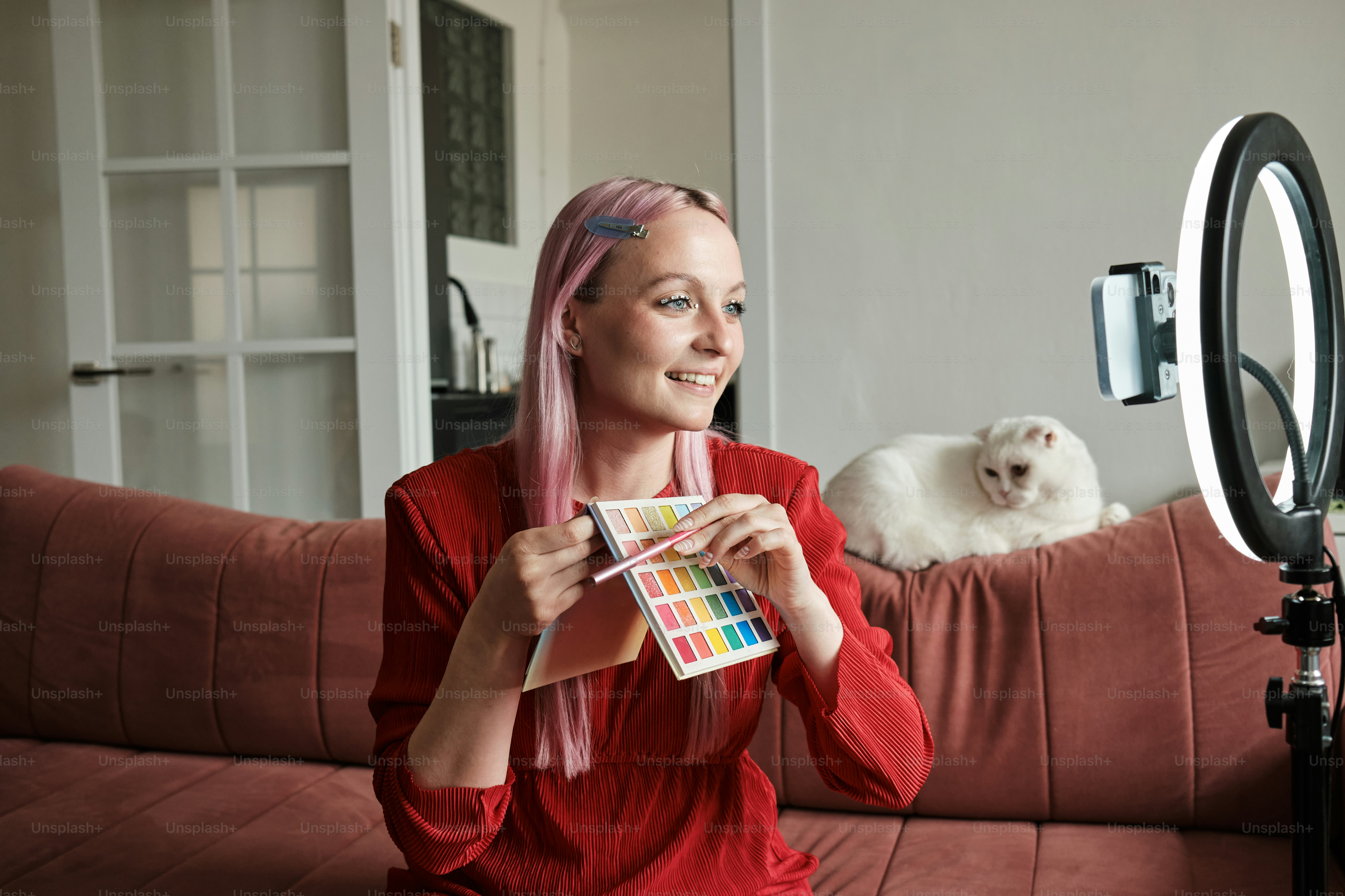 seorang wanita duduk di sofa dengan seekor kucing di belakangnya