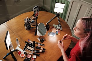 a woman sitting at a table with makeup and a cell phone