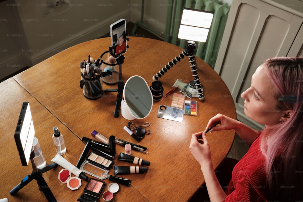 a woman sitting at a table with makeup and a cell phone