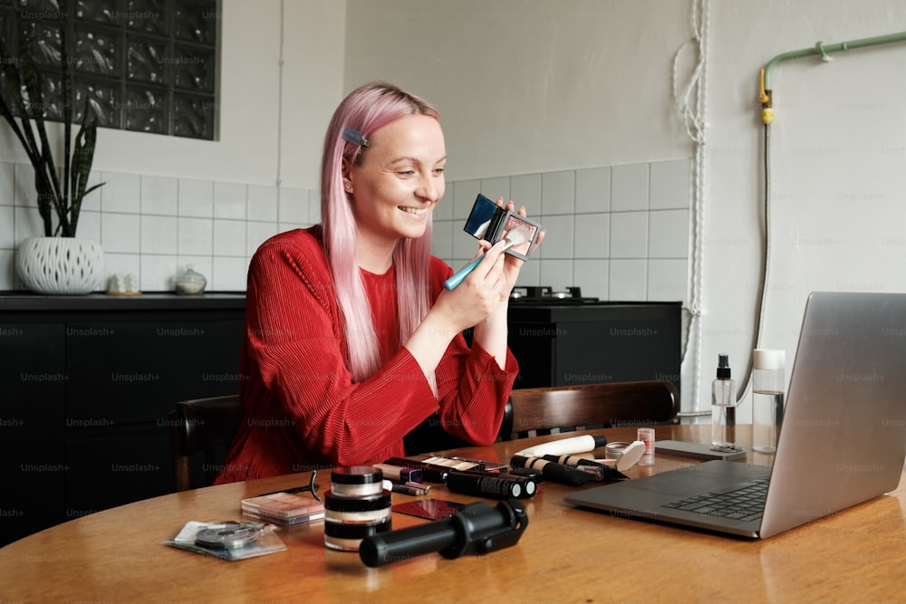 Une femme assise à une table avec un ordinateur portable et un appareil photo