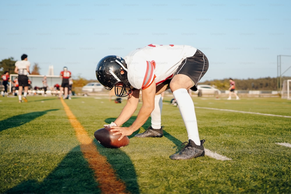 a football player bending down to pick up a ball