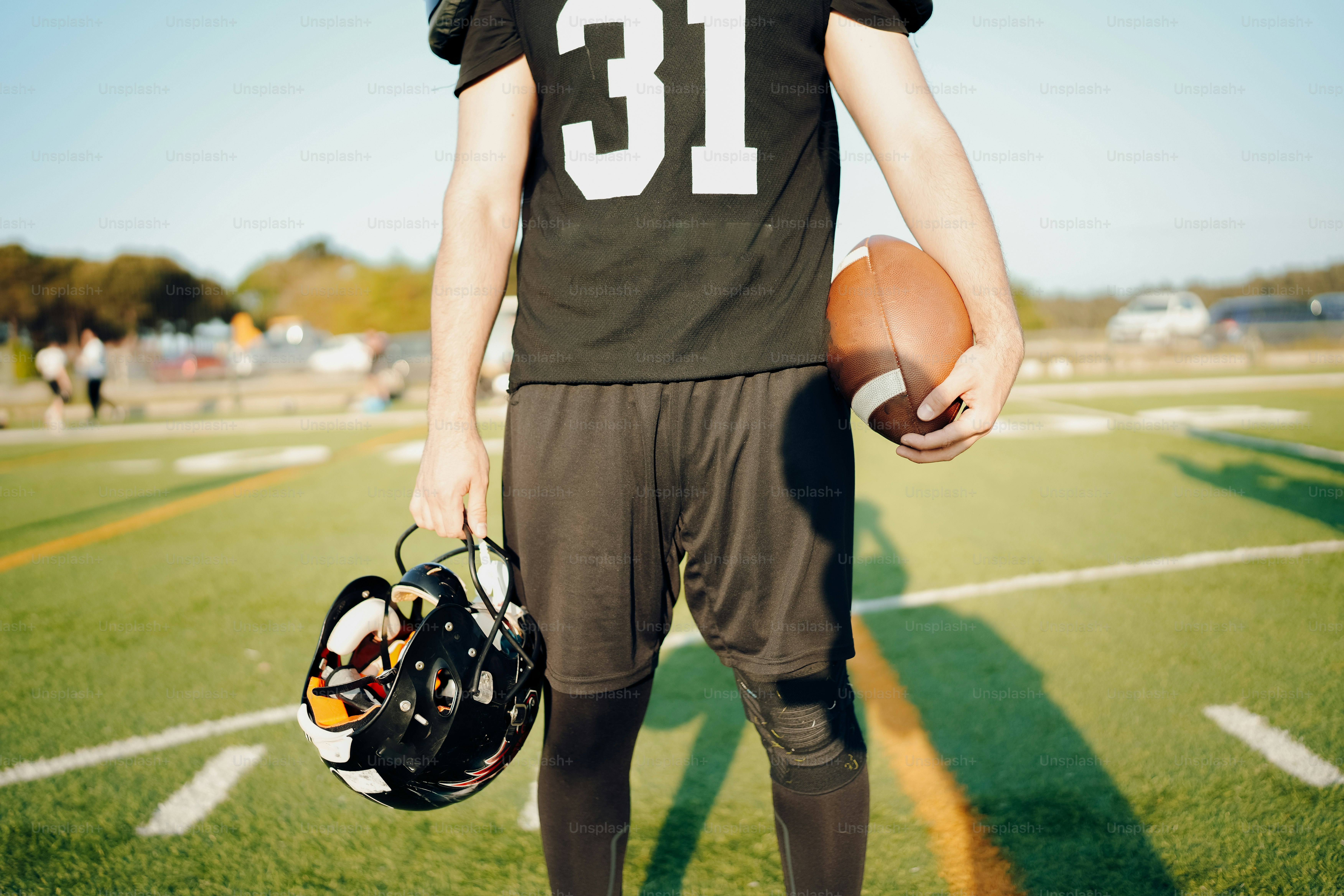 a football player holding a football and a helmet