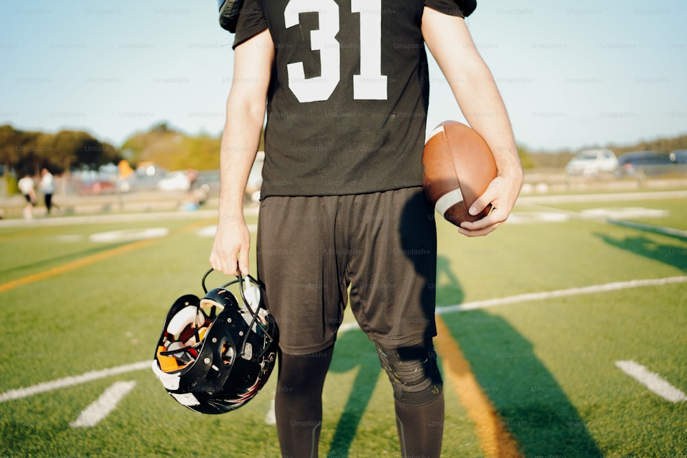 a football player holding a football and a helmet