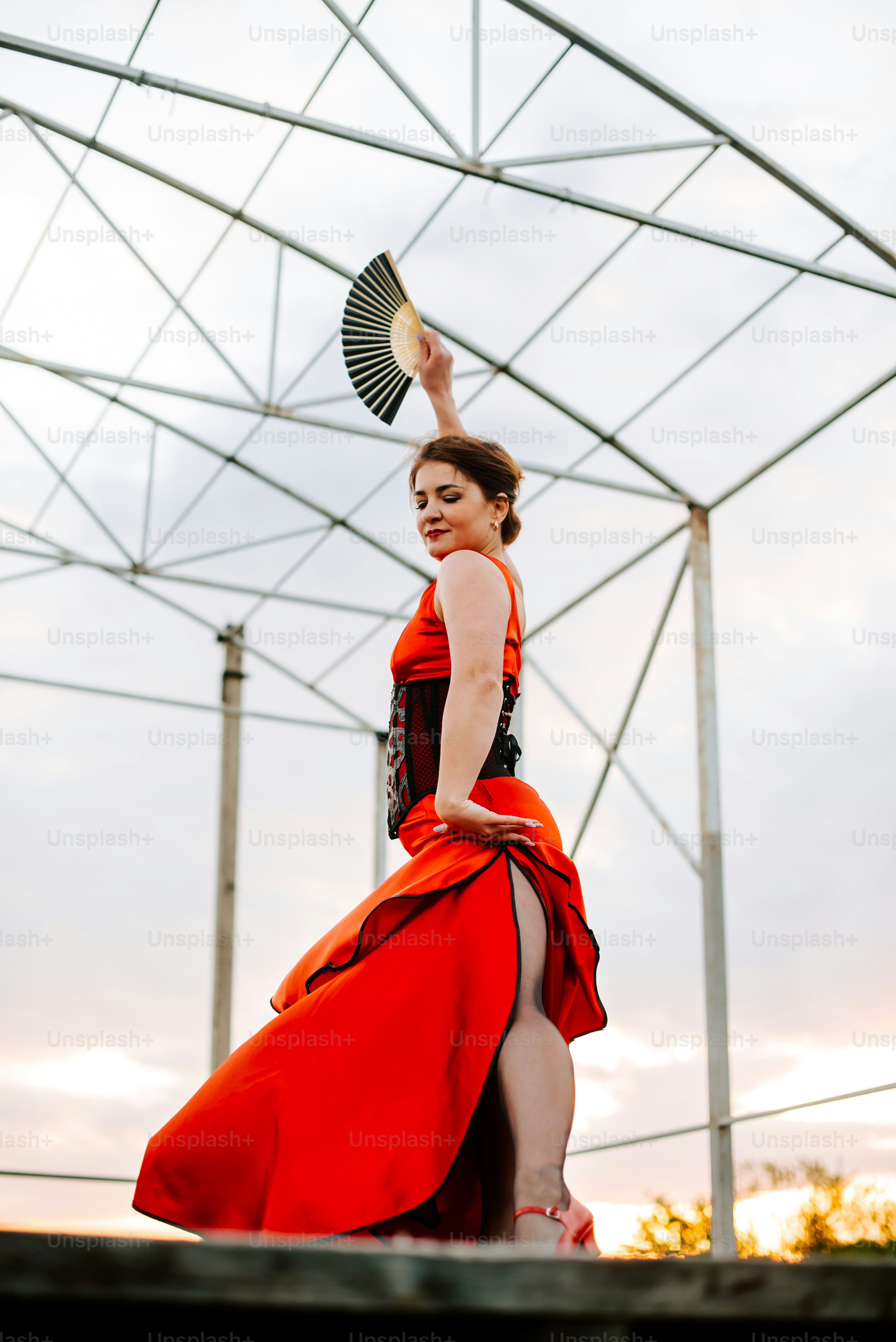 Une femme en robe rouge tient un éventail