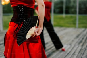 Una mujer con un vestido rojo sosteniendo un abanico negro