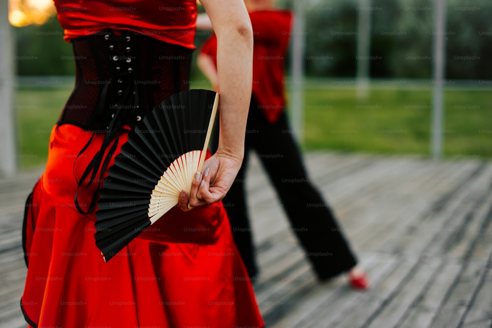 a woman in a red dress holding a black fan