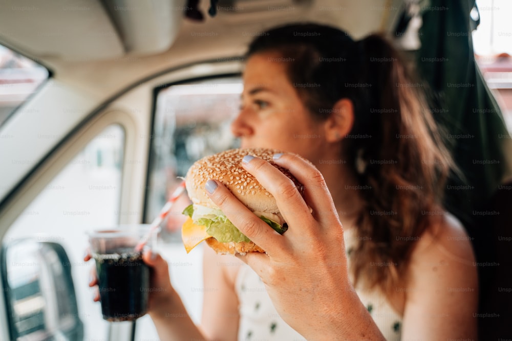 Una donna seduta in una macchina che mangia un panino