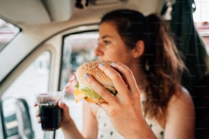 Une femme assise dans une voiture en train de manger un sandwich