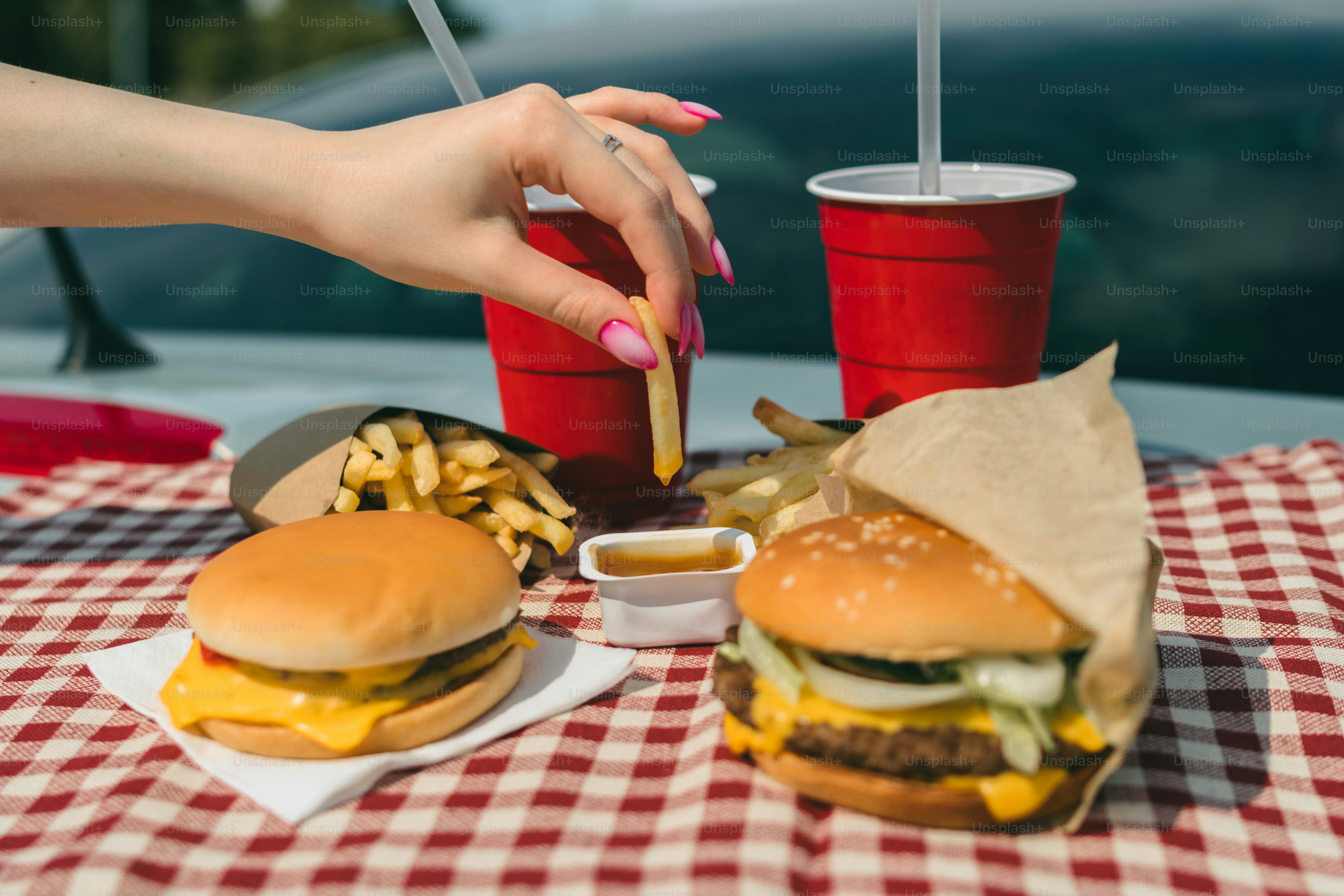 a woman is eating a hamburger and french fries