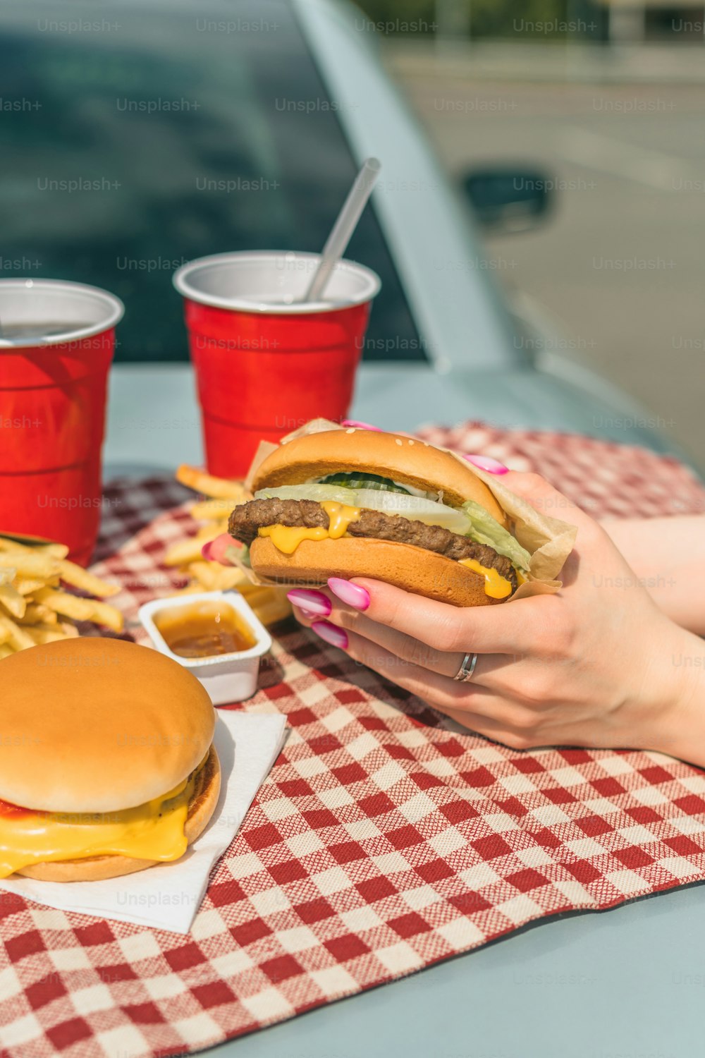 Una donna che mangia un hamburger e patatine fritte