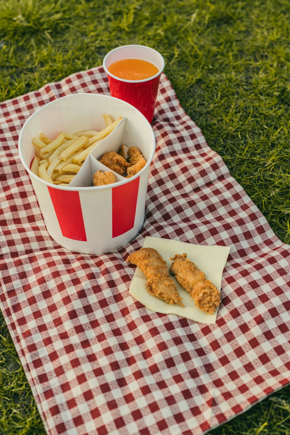 a red and white checkered table cloth with a bowl of fries and a cup